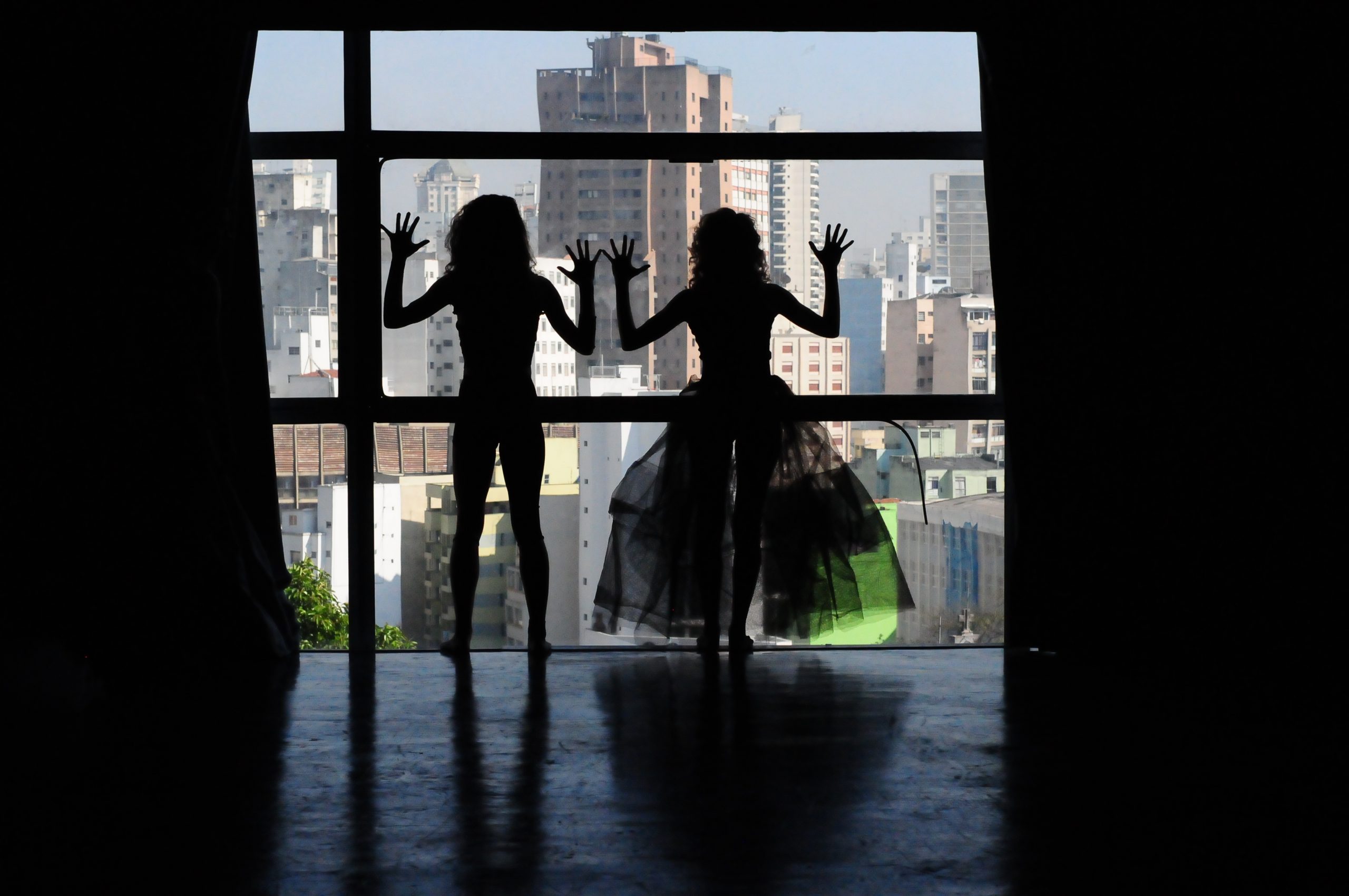 Dois estudantes da SP Escola de Teatro na janela de um prédio em experimento cênico