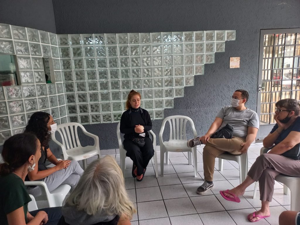 Estudantes da SP Escola de Teatro e idosos do Centro de Acolhida Especial sentados em círculo em atividade de contrapartida