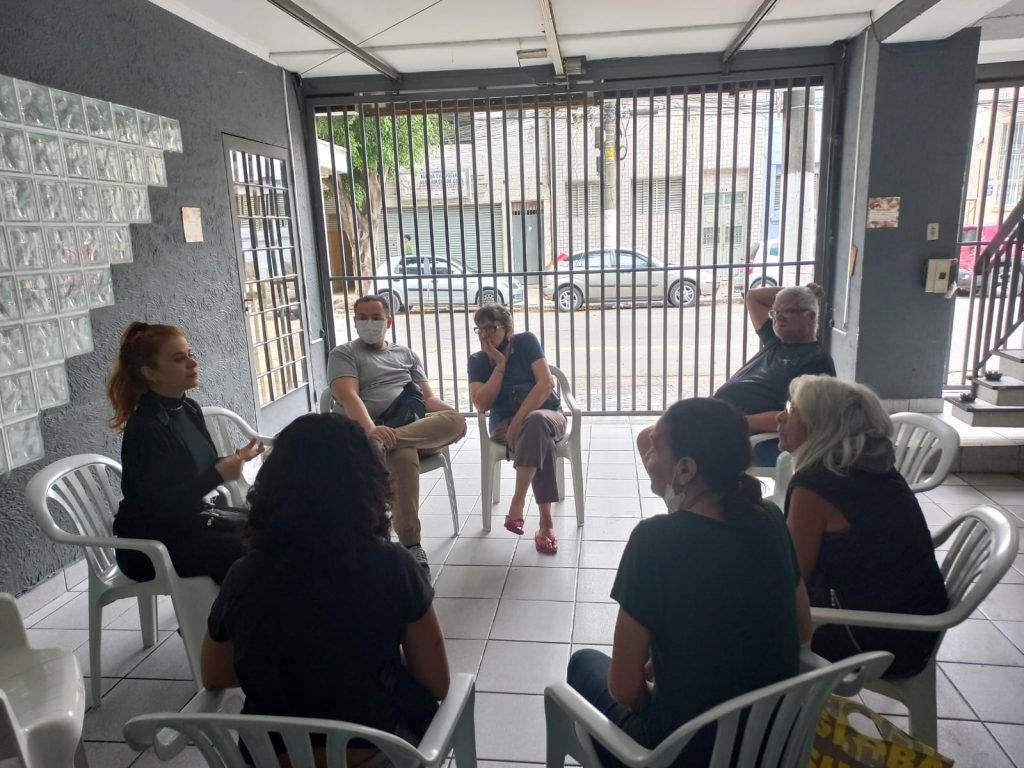 Estudantes da SP Escola de Teatro e idosos do Centro de Acolhida Especial sentados em círculo em atividade de contrapartida