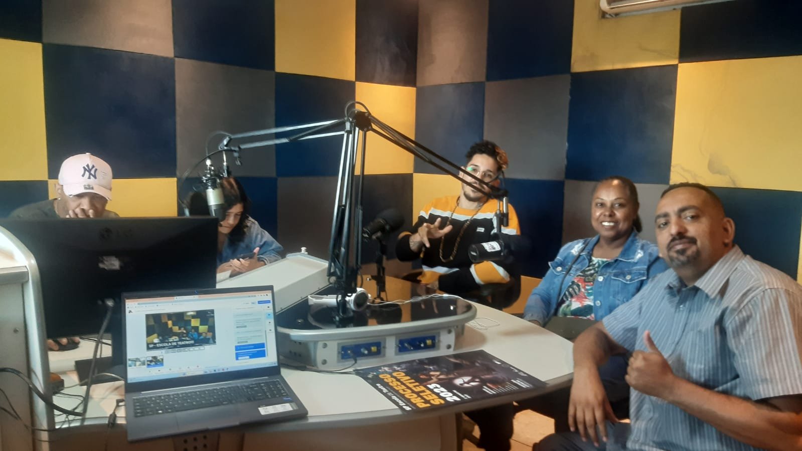 Foto colorida no estúdio da Rádio Comunitária Heliópolis, com João Martins e Mônica Madureiro, colaboradores da SP, e Ana, Reginaldo e Wagner, representantes da rádio e da Unas