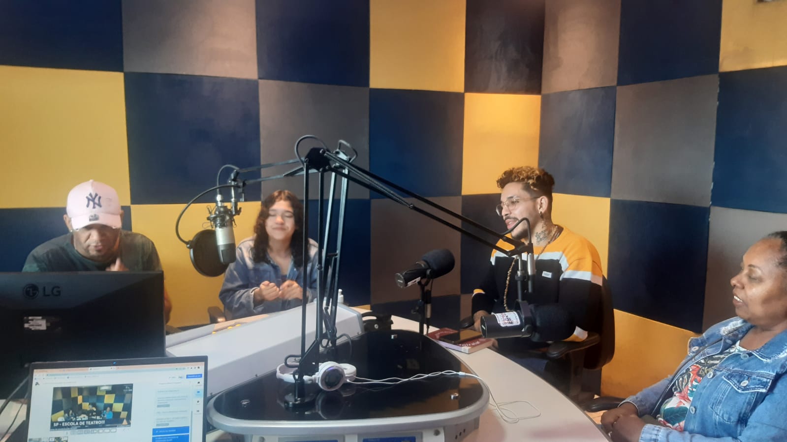 Foto colorida no estúdio da Rádio Comunitária Heliópolis, com João Martins e Mônica Madureiro, colaboradores da SP, e Ana, Regis, Genario e Waguininho, representantes da rádio e da Unas
