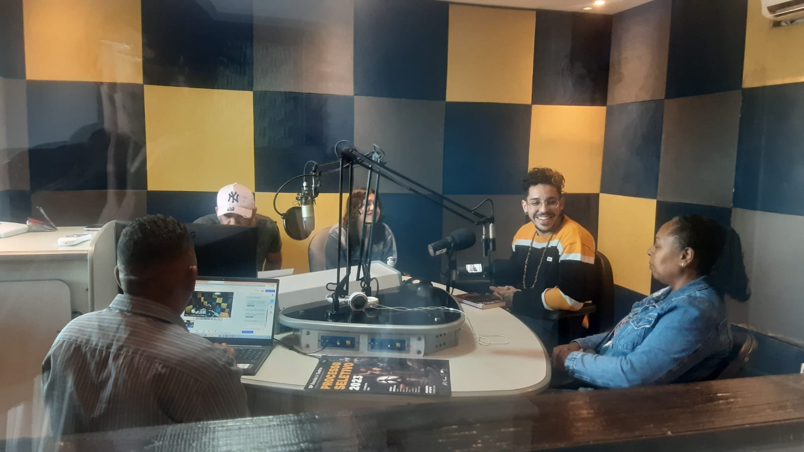 Foto colorida no estúdio da Rádio Comunitária Heliópolis, com João Martins e Mônica Madureiro, colaboradores da SP, e Ana, Reginaldo e Wagner, representantes da rádio e da Unas