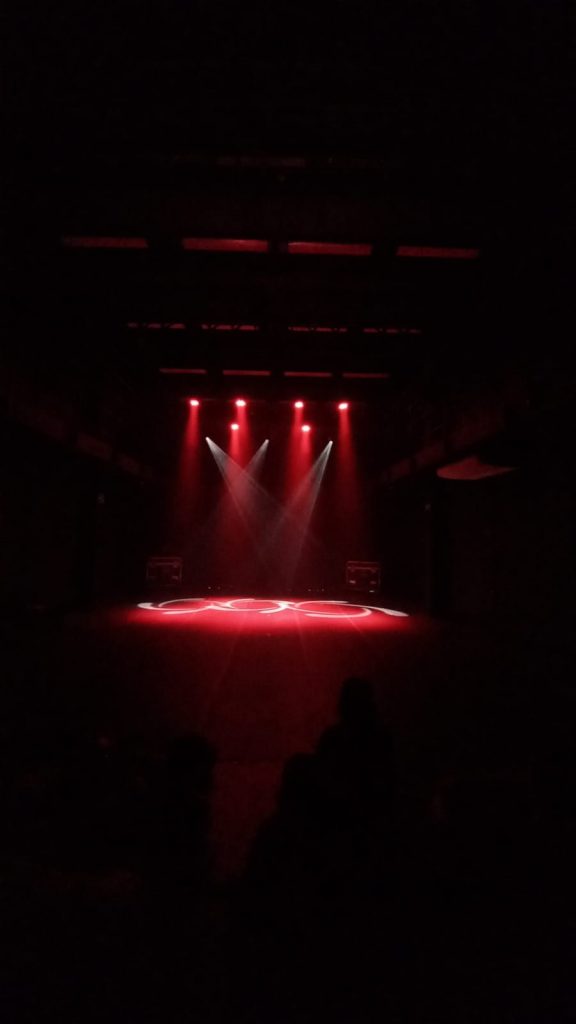 Foto mostrando o palco sob o efeito das luzes vermelha e branca