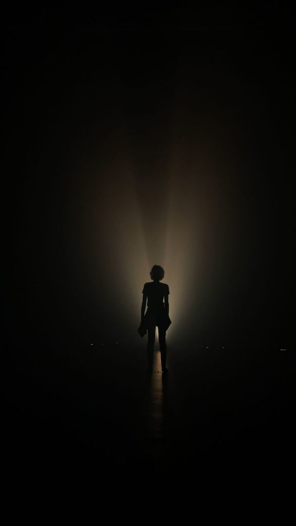 Foto com luz escura mostrando a silhueta de uma pessoa contra a luz