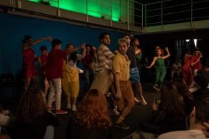 Fotografia colorida mostrando cena da apresentação de encerramento do curso de extensão cultural de Teatro Musical