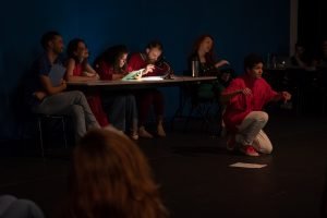 Fotografia colorida mostrando os integrantes do curso de extensão cultural de "Teatro Musical" em apresentação de encerramento