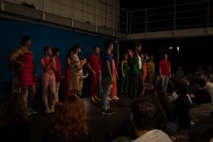 Fotografia colorida mostrando os integrantes do curso de extensão cultural de "Teatro Musical" em apresentação de encerramento