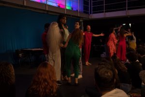 Fotografia colorida mostrando os integrantes do curso de extensão cultural de "Teatro Musical" em apresentação de encerramento