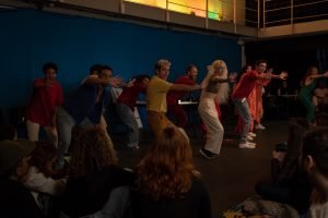 Fotografia colorida mostrando os integrantes do curso de extensão cultural de "Teatro Musical" em apresentação de encerramento