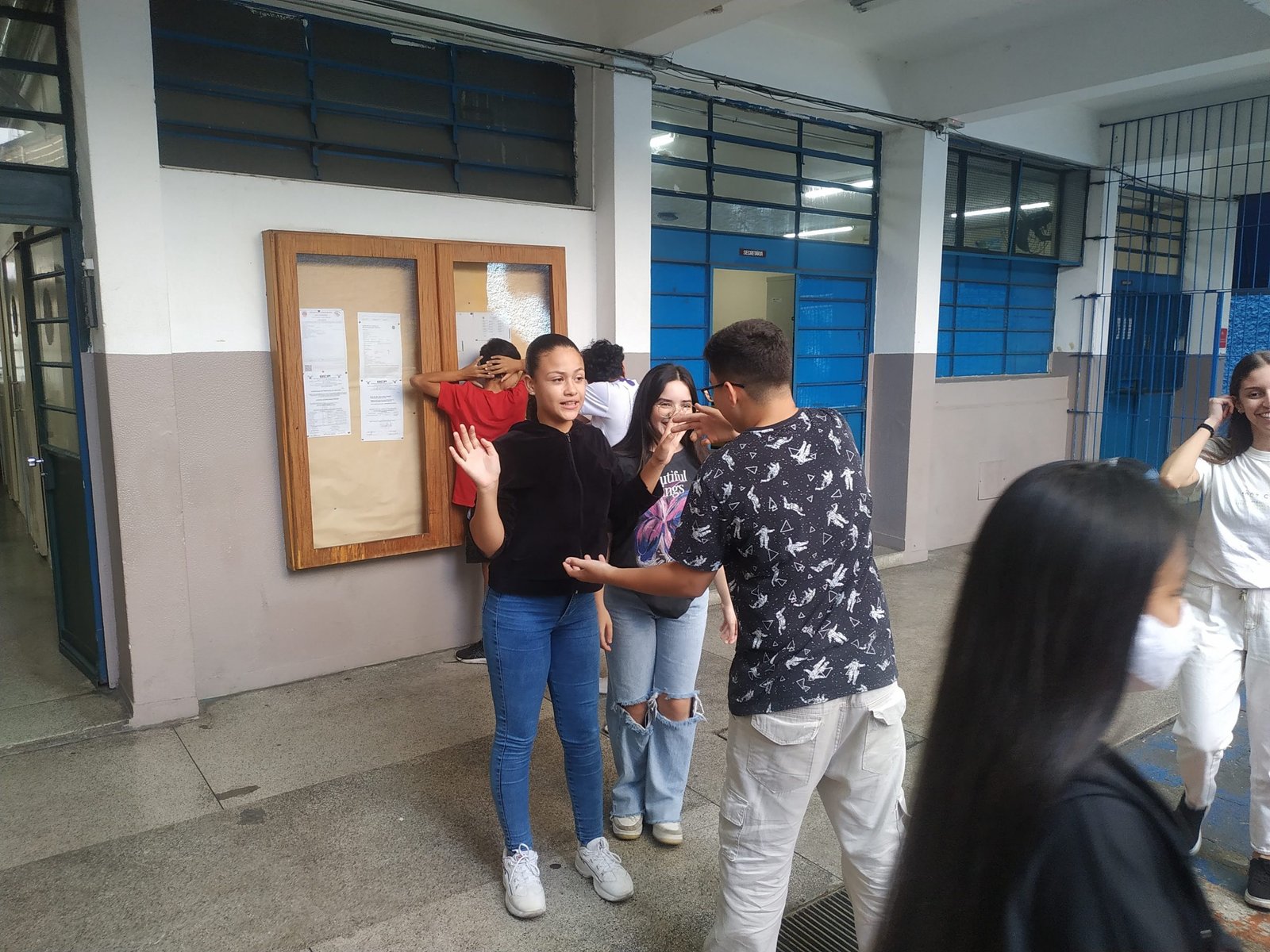 Fotografia colorida mostrando três estudantes da E.E. Eduardo Prado em oficina de jogos teatrais