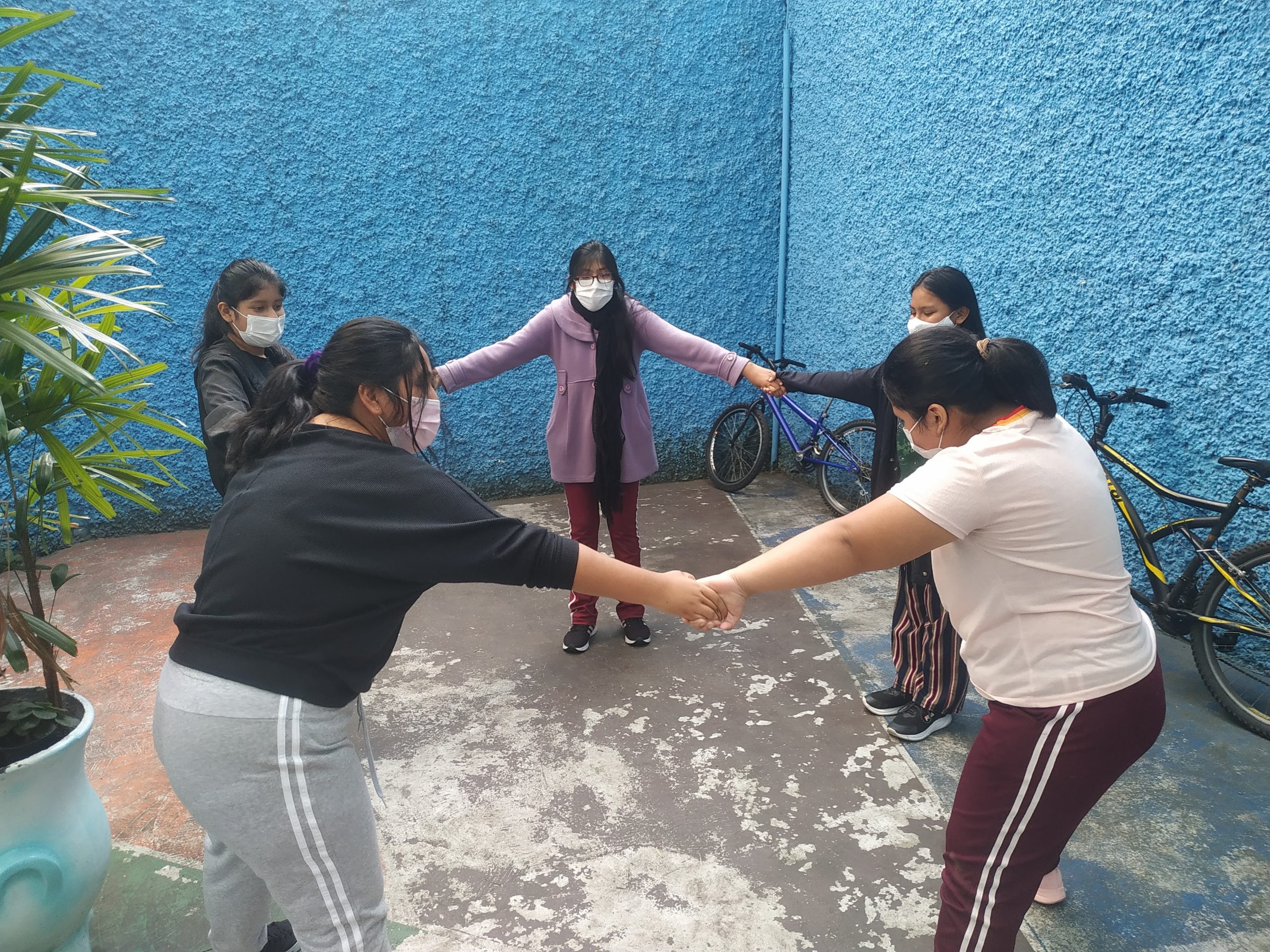 Fotografia colorida mostrando as estudantes da E.E. Eduardo Prado de mãos dadas em círculo 