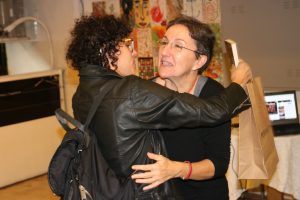Fotografia colorida mostrando Tiche Vianna abraçando uma convidada do lançamento do livro.