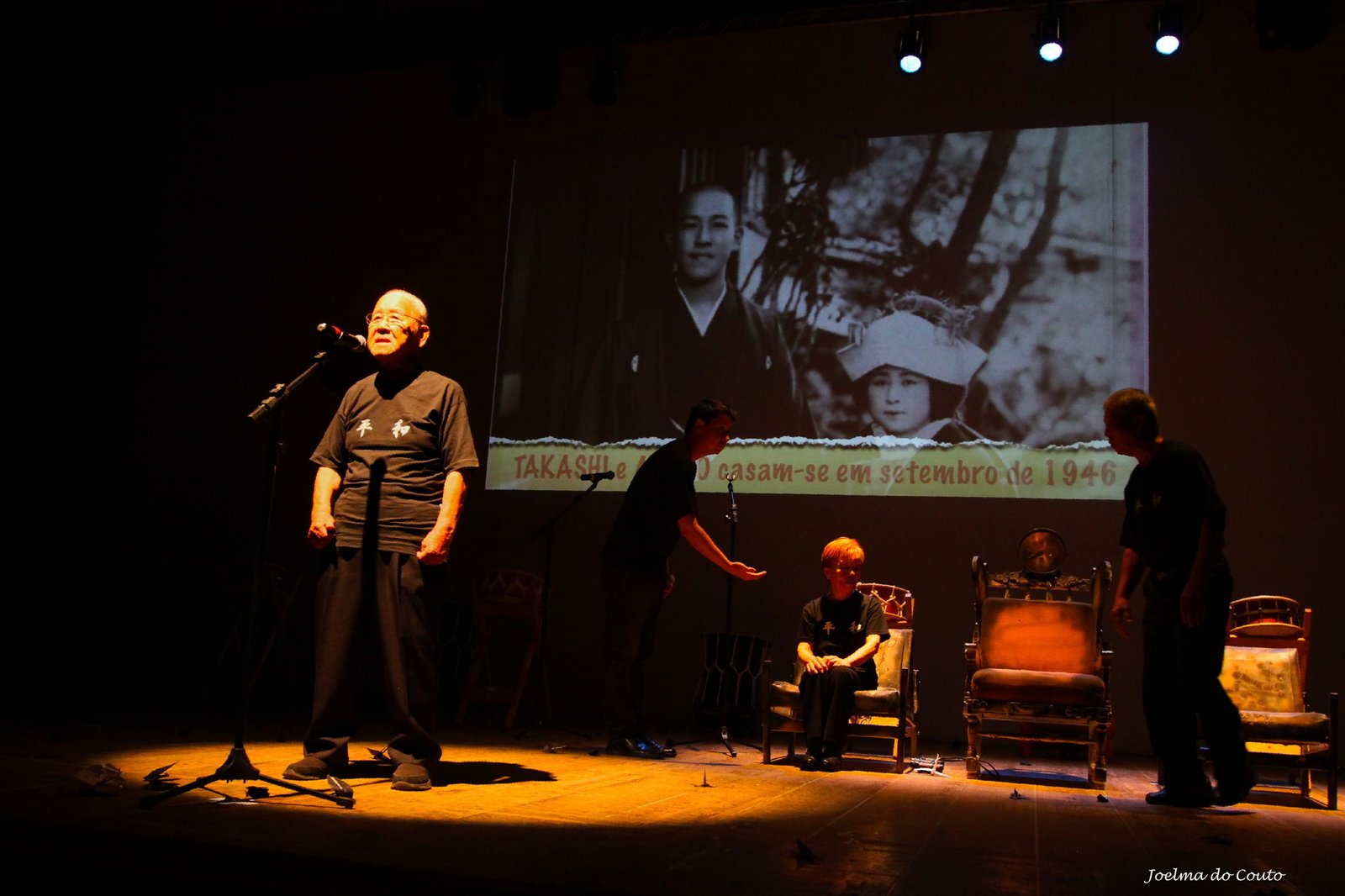 Foto colorida mostra homem no palco, durante apresentação de peça