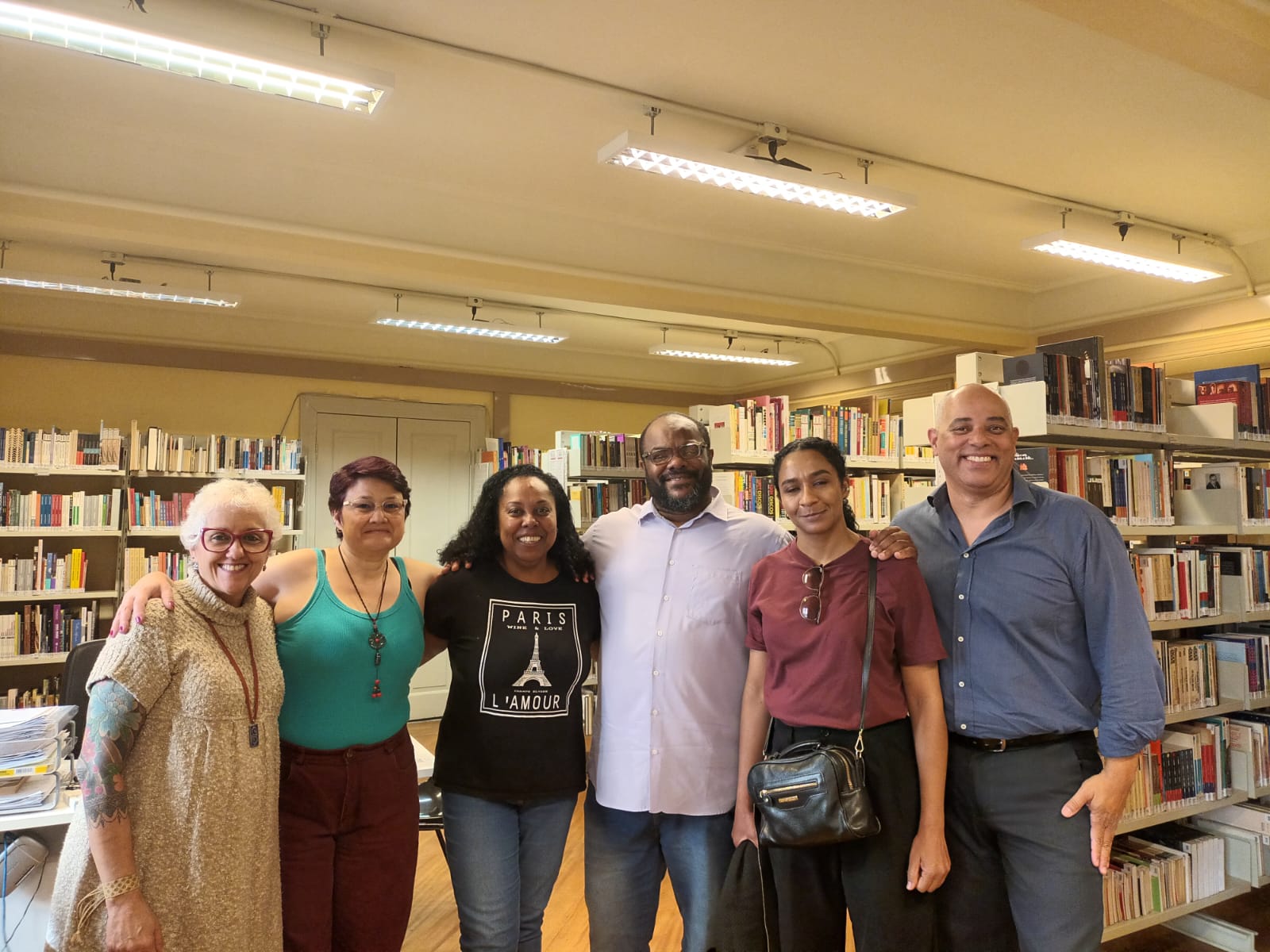 Fotografia colorida de Monica Madureiro com os professores da UNIFAI na biblioteca da SP Escola de Teatro