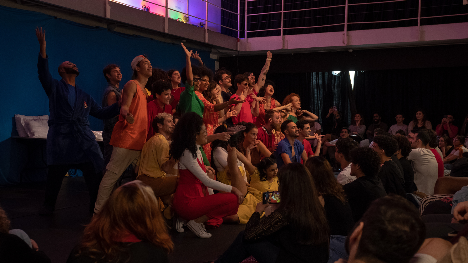 Fotografia colorida mostrando os integrantes do curso de extensão cultural de "Teatro Musical" em apresentação no encerramento