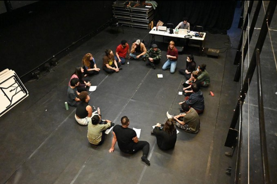 Fotografia colorida da turma do workshop "A Plástica Cênica" sentada em círculo