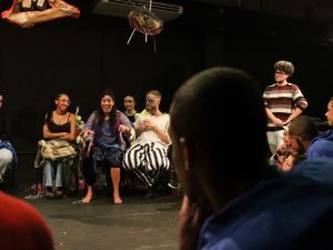 Fotografia de grupo de jovens da Fundação CASA assistindo experimento cênico