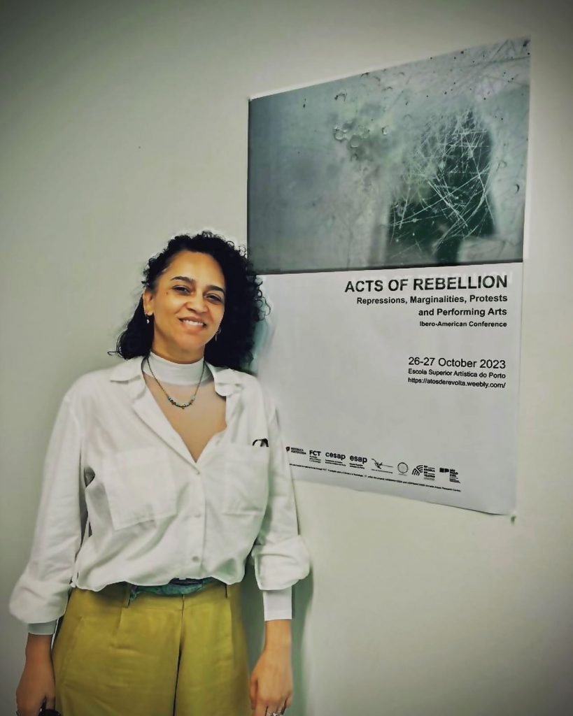 Heloisa Rocha, mulher com cabelos pretos cacheados na frente de um quadro na ESAP em Porto, Portugual.